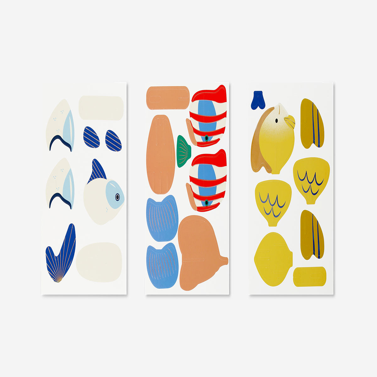 Three DIY cardboard fish craft kits from Flying Tiger Copenhagen, colorful and ready for assembling in a hobby activity setting.