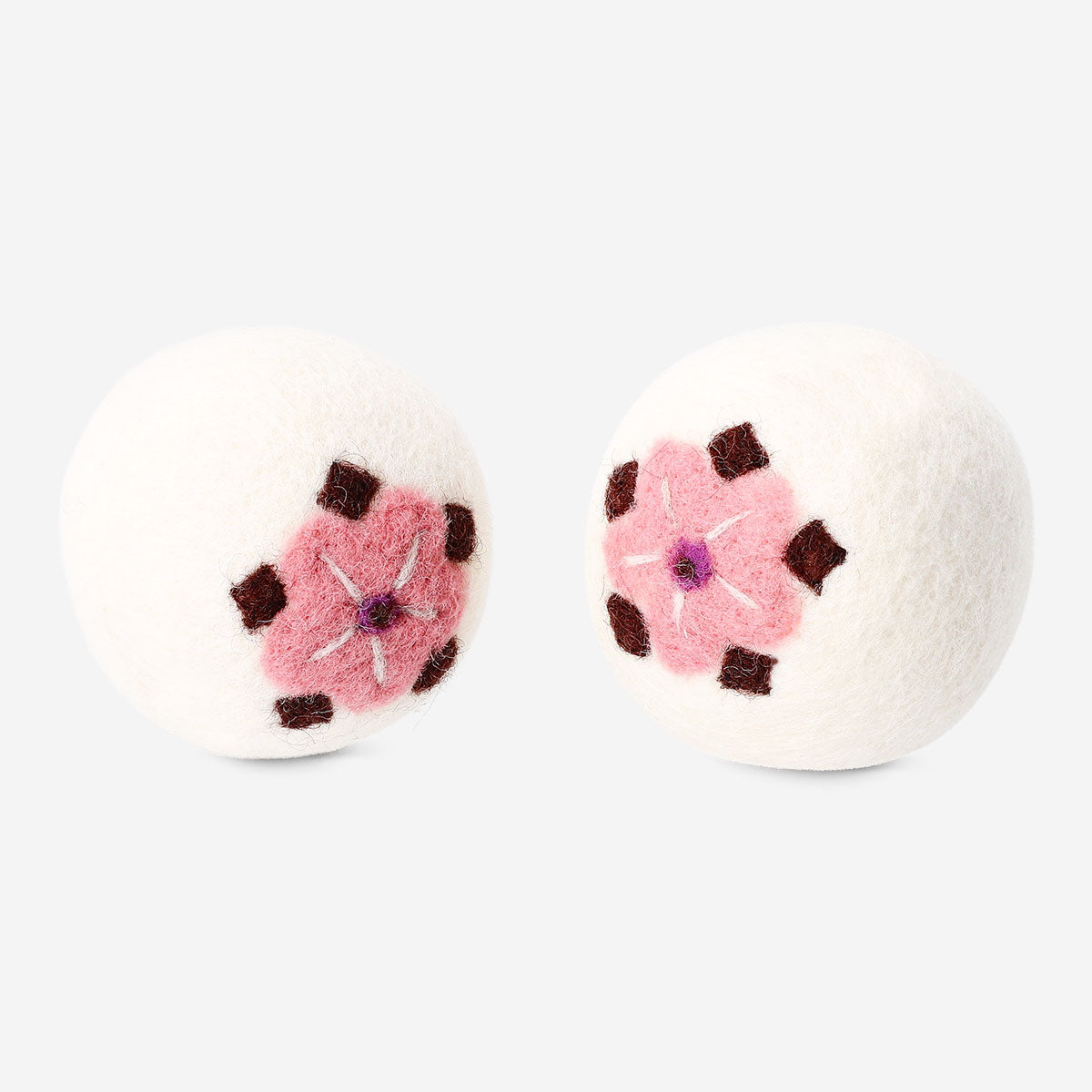 Two Wool laundry balls with flower motifs from Flying Tiger Copenhagen, used for eco-friendly fabric softening and laundry care.